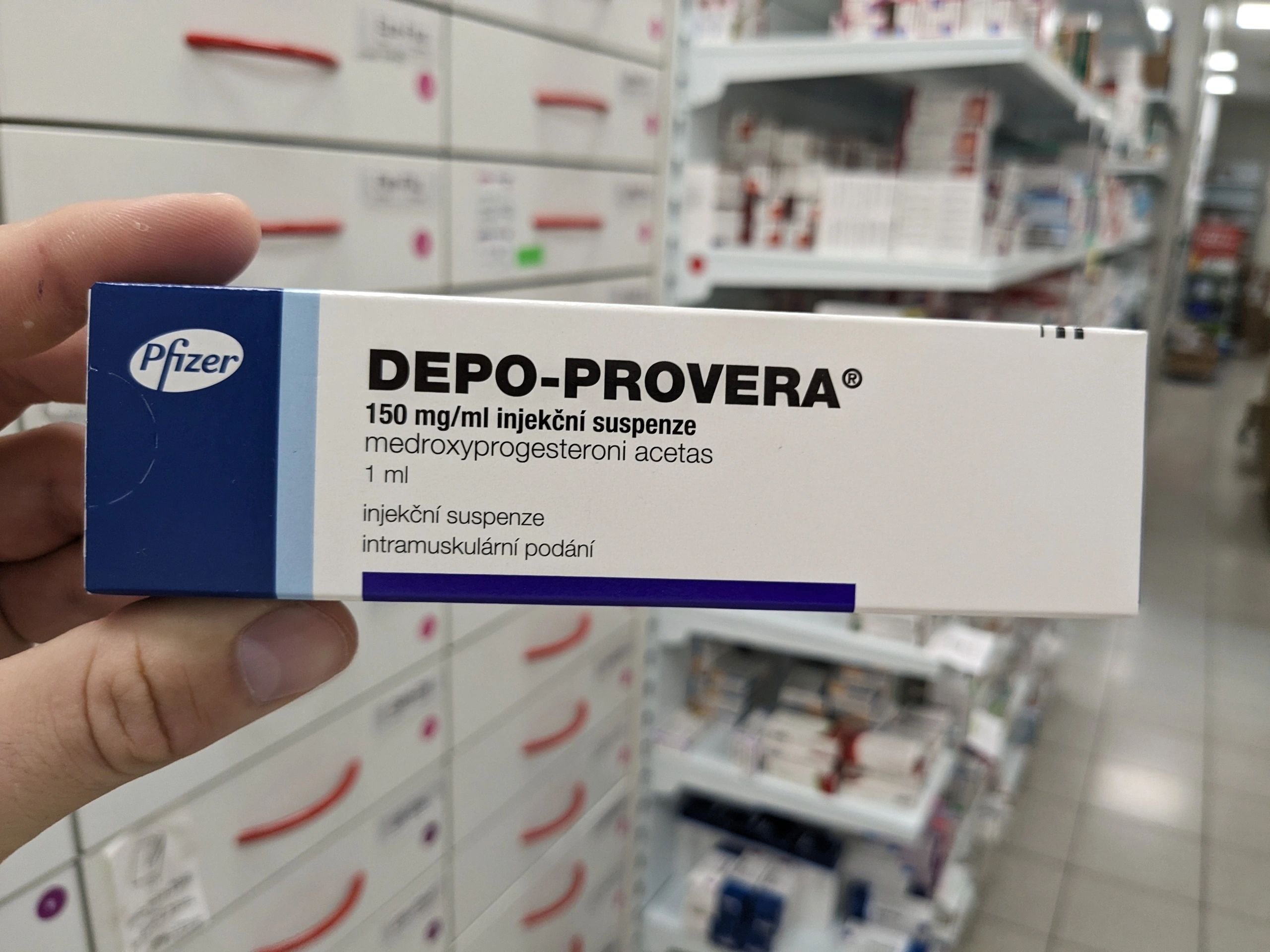 Hand holding a box of Depo-Provera in a pharmacy